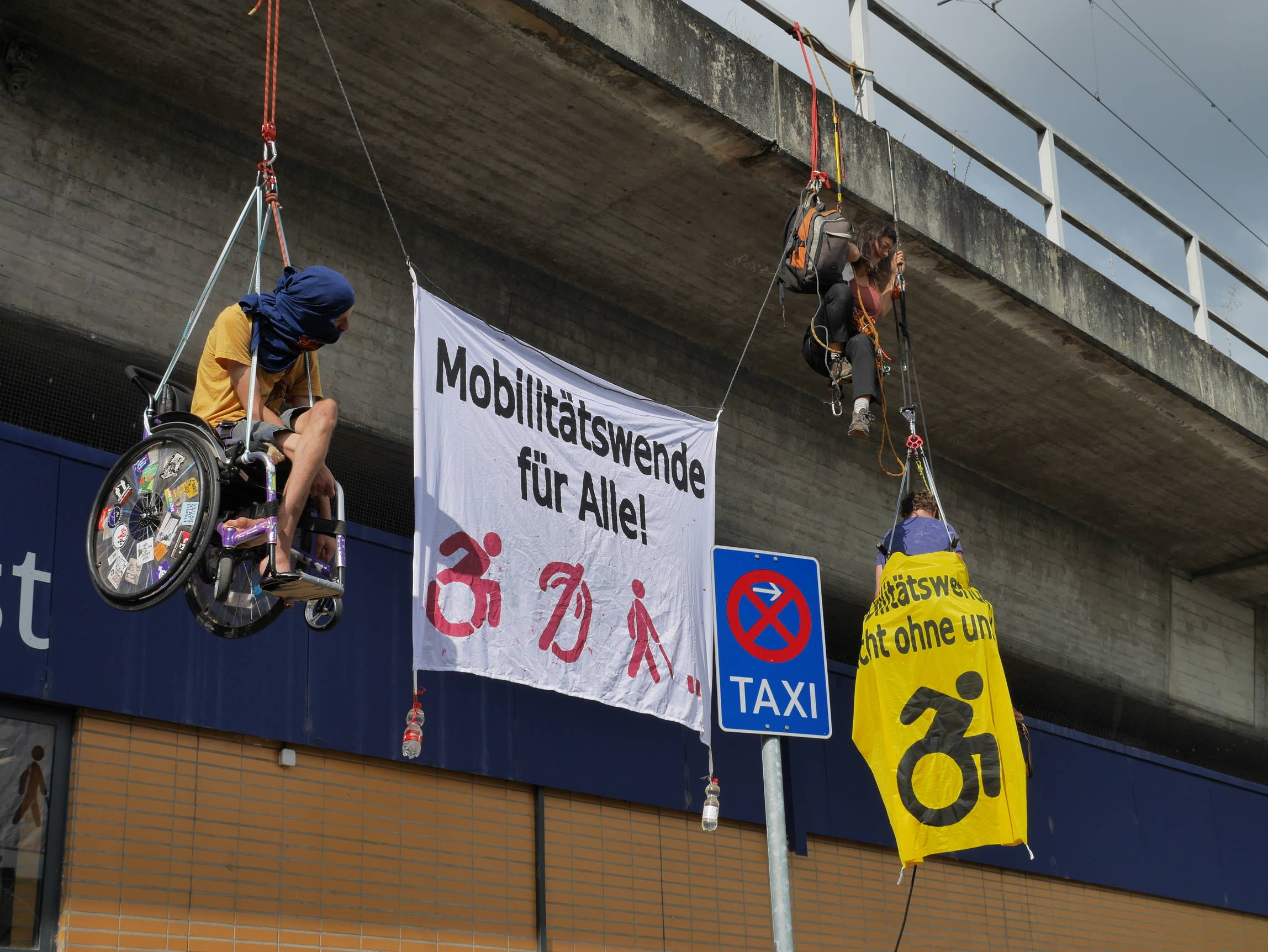 nahaufnahme Banner Aktion, 2 Rollstuhlfahrer*innen und ein Banner Mobilitätswende für alle udn ein Banner Mobilitätswende nicht ohne uns
