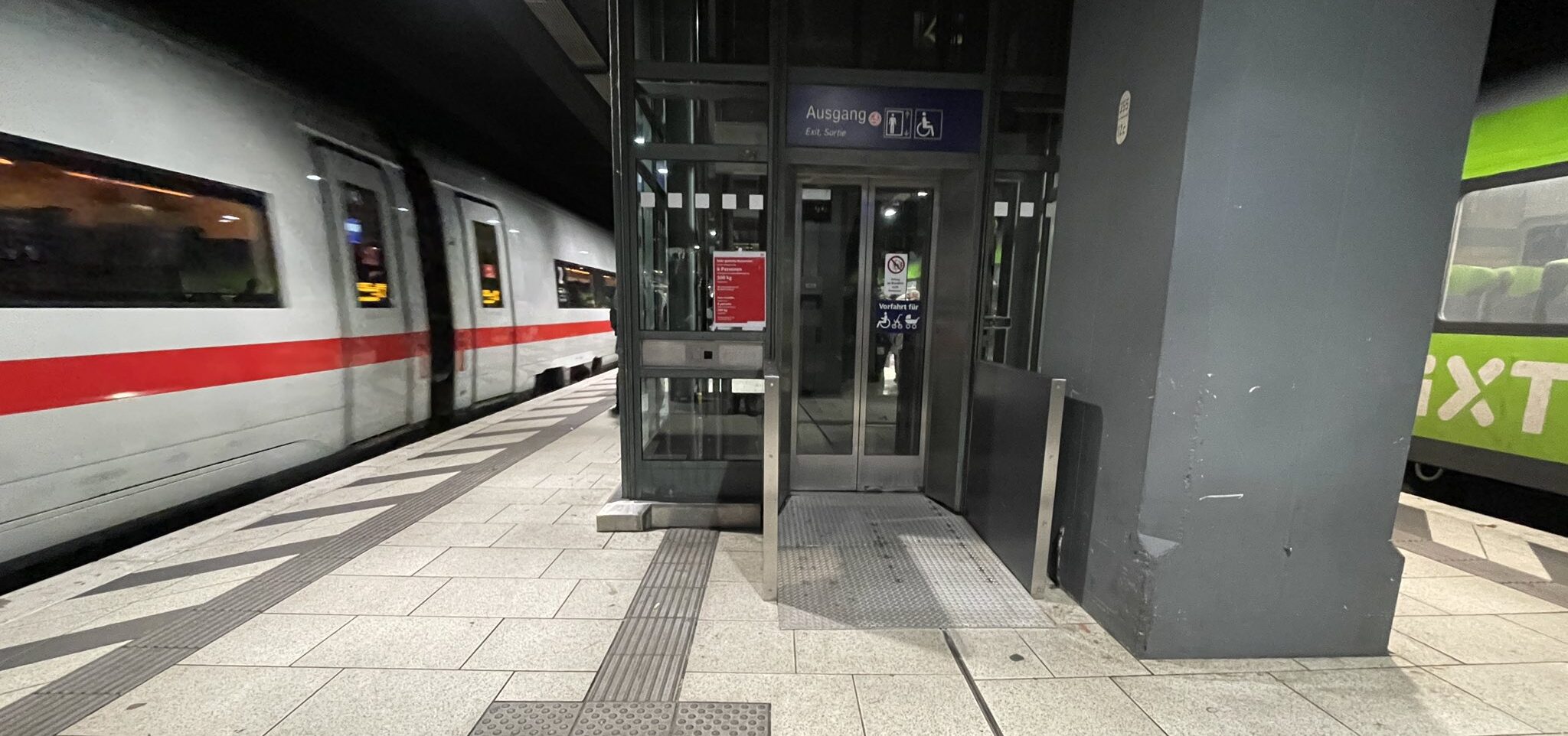 Aufzug auf Gleis 13 am Hamburger Hauptbahnhof. Eingang durch Rampe und Wände rechts und Links verengt, Blindenleitsystem führt neben der Rampe gegen die Wand zum Aufzug-Rufknopf