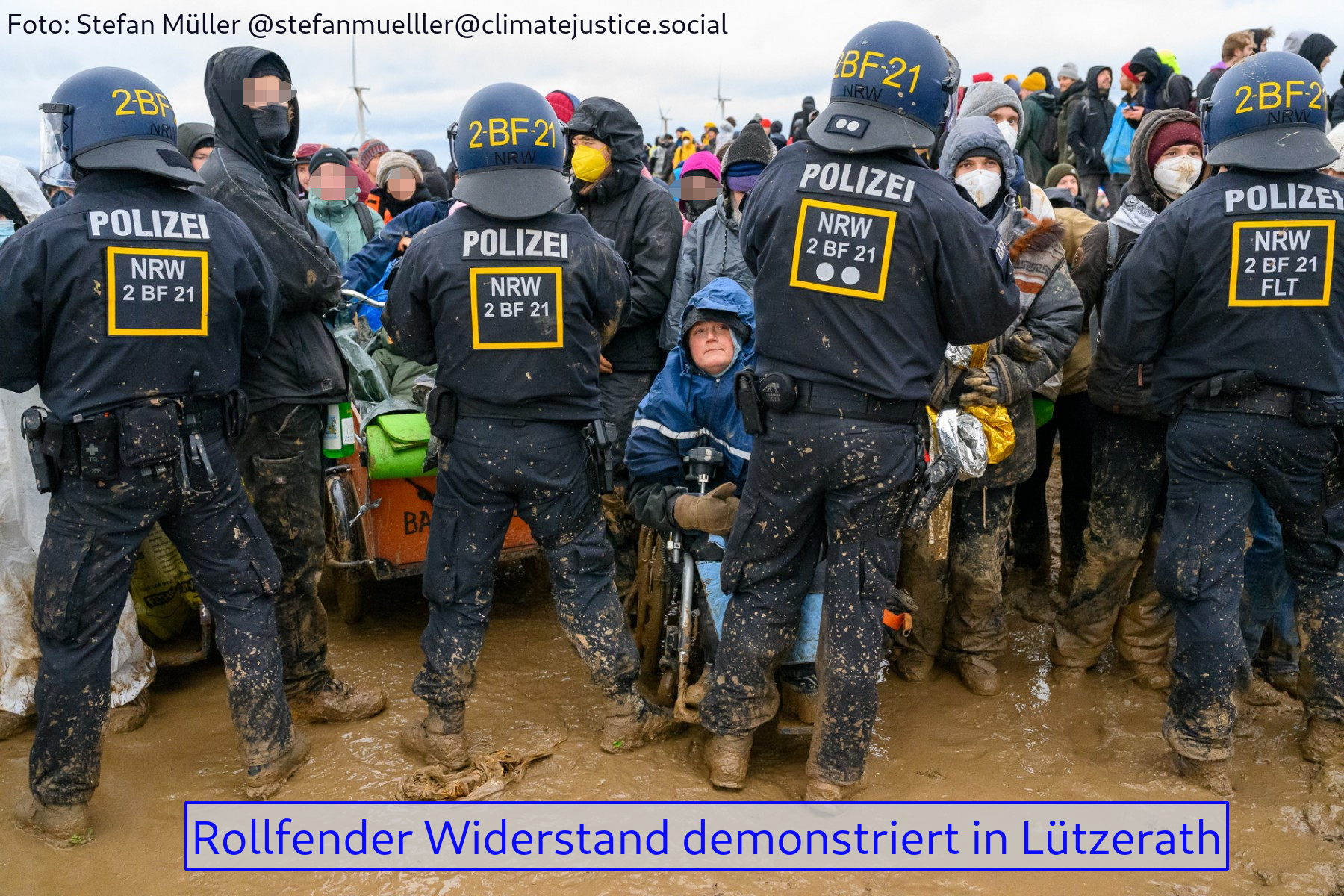 Polizisten stehen Demonstranten gegenüber und hindern sie daran, weiter in Richtung Lützerath vorzudringen. Eine Person sitzt im Rollstuhl. vor Lützerath, 14.02.23
