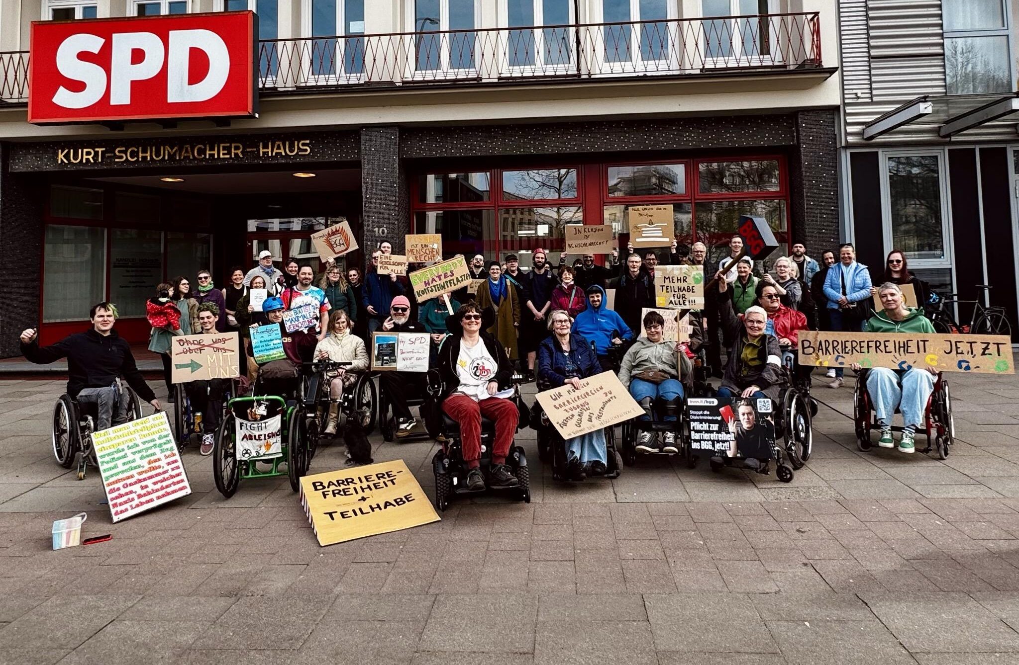 Gruppenbild bei der Demo vor der SPD Zentrale in Hamburg. ca. 40 Menshcen mit Plakaten, Und eine Rampe aus Pappkarton und einen "BGG" Hammer