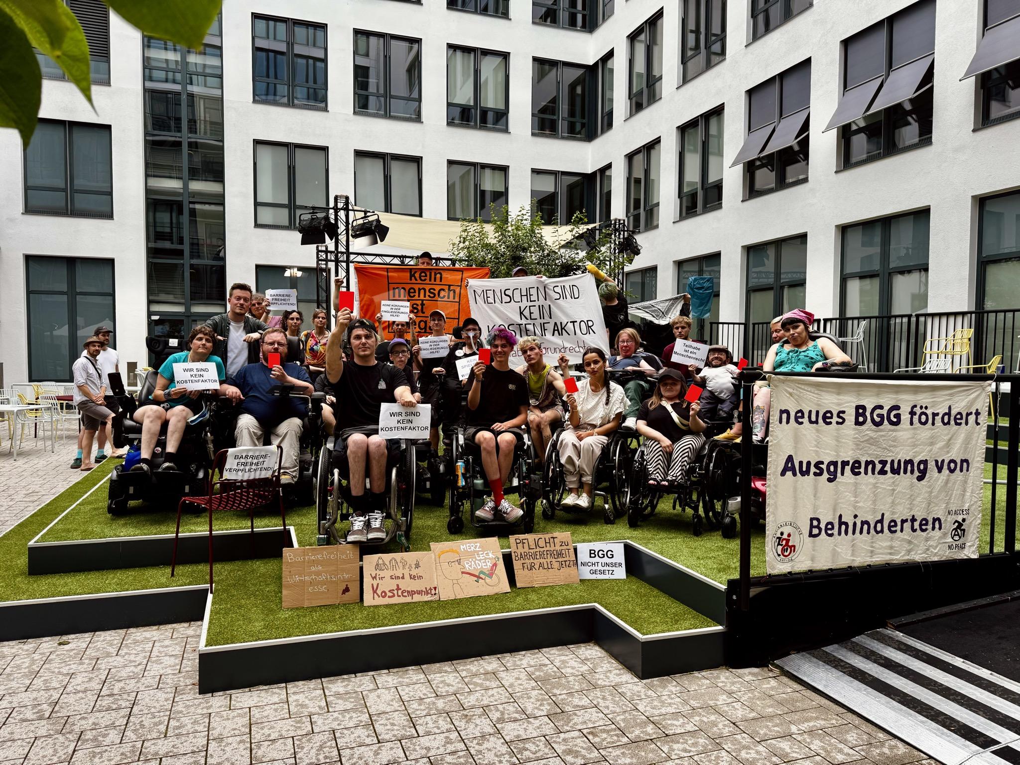 Gruppenbild. Aktivisitis mit und ohne Rollstühle mit Plakaten gegen das BGG und Banner "neues BGG fördert Ausgrenzung von Behinderten"
